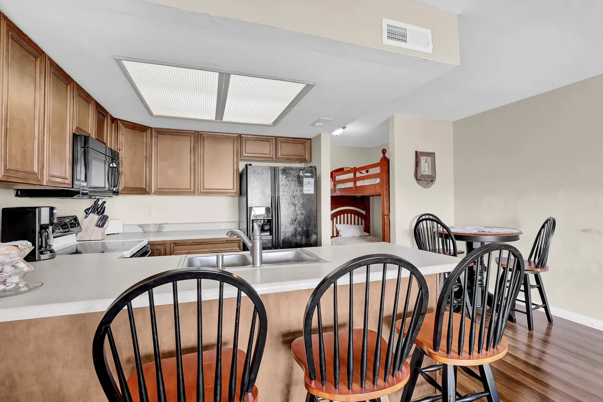 A cozy, family-friendly kitchen space with a kitchen island, bar stools, and adjacent bunk beds. The scene captures people preparing meals together and sharing stories over breakfast, highlighting the experience of cooking fresh seafood in a well-equipped kitchen.